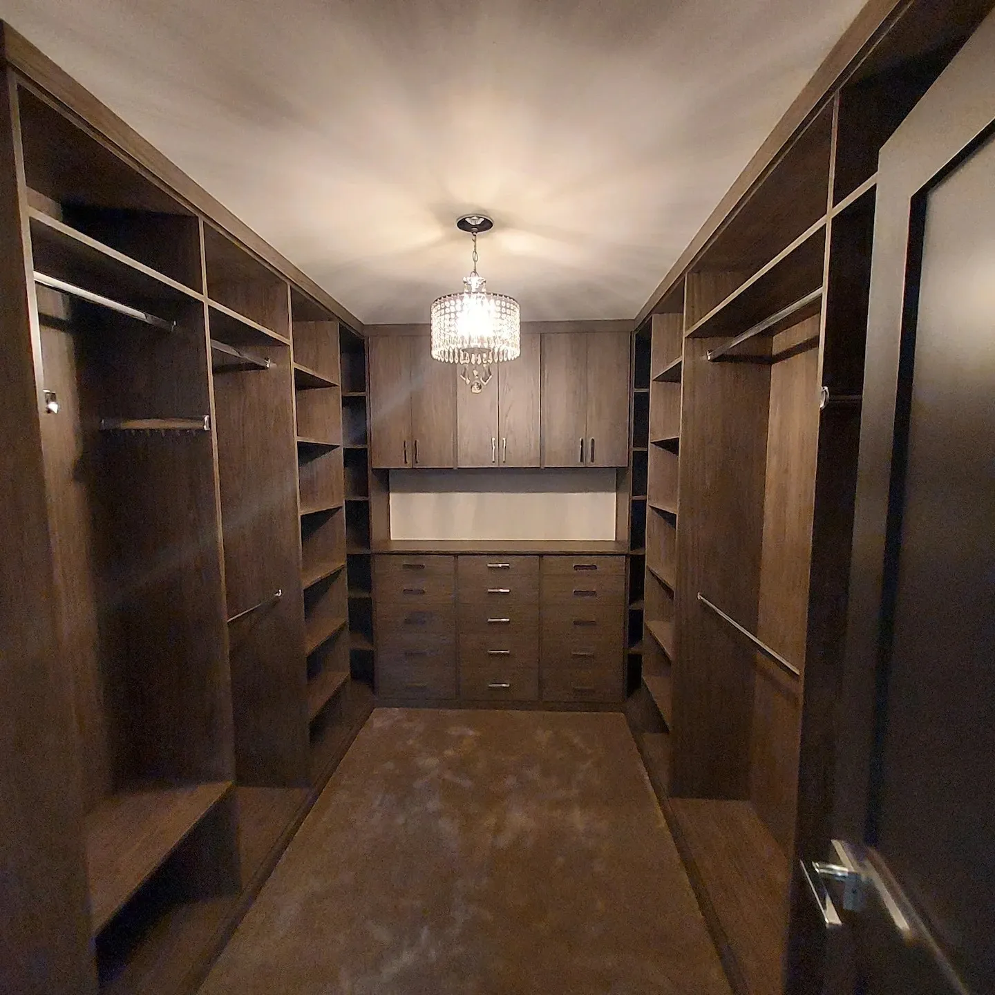 A walk in closet with many wooden shelves and drawers.