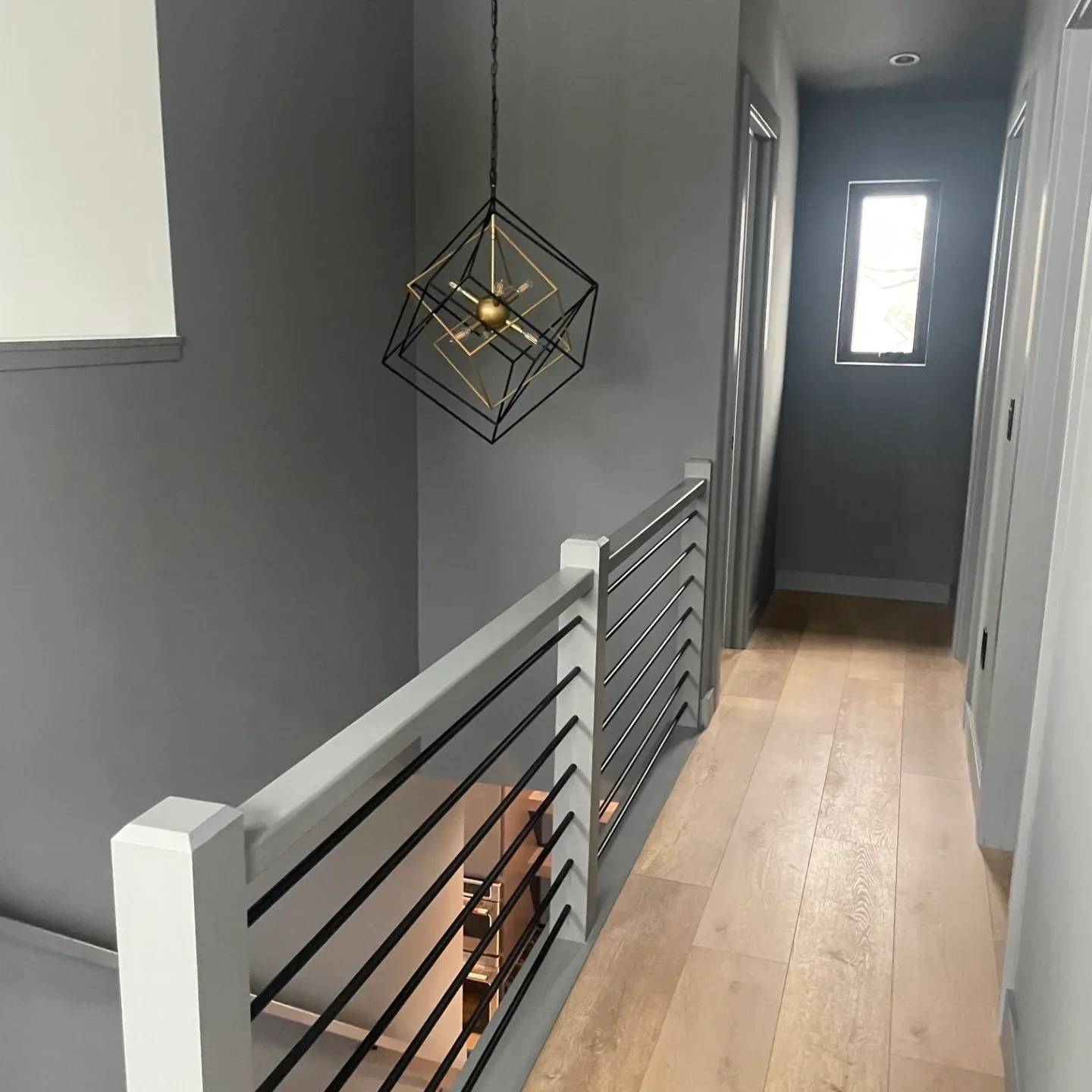 A hallway with a metal railing and wooden floors.