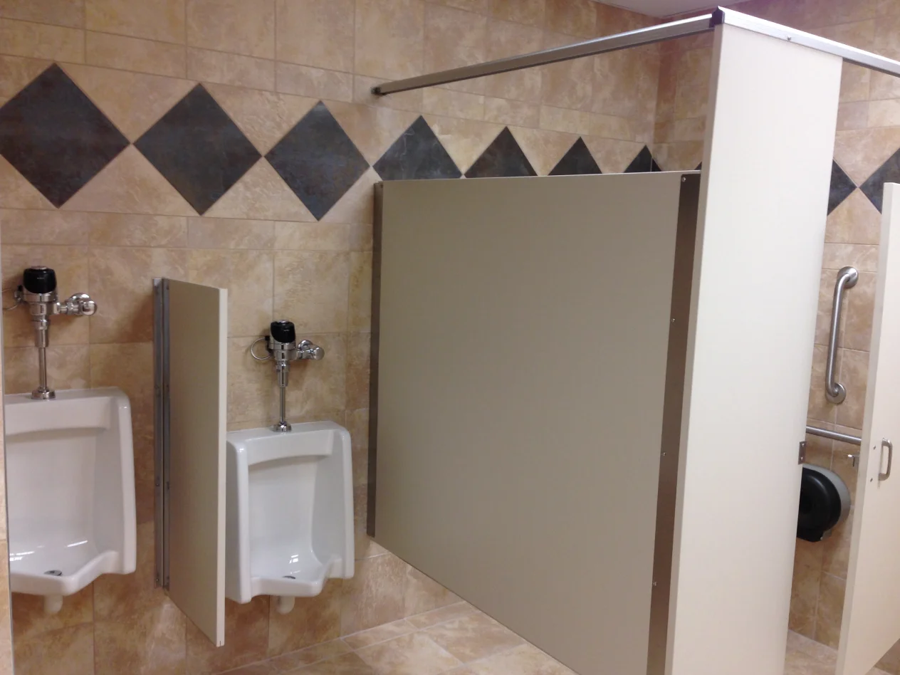 A bathroom with a urinal and a shower stall.